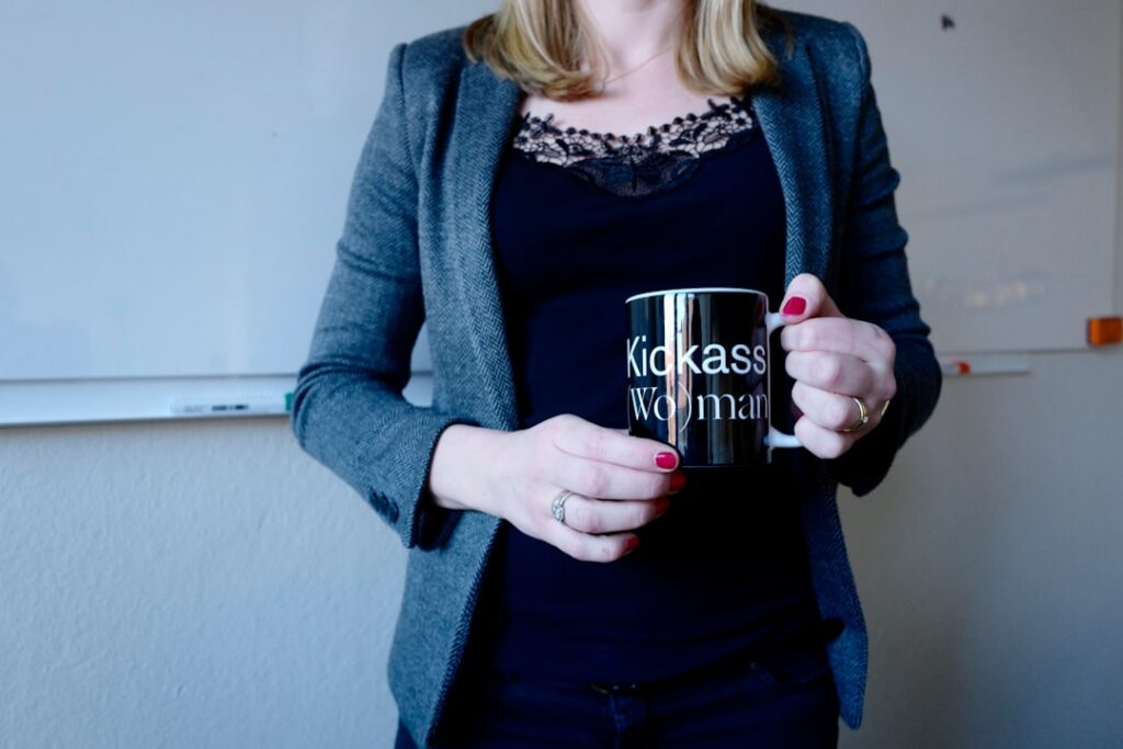 From Long Shot to Leader: KPMG's 30-Year Rise woman wearing blue cardigan holding black mug