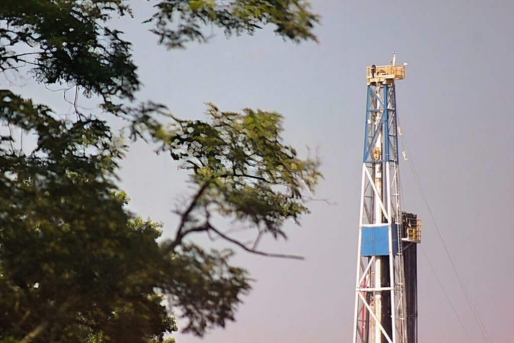 Diversified Energy Acquires Maverick Natural Resources a blue and white drilling rig next to a tree