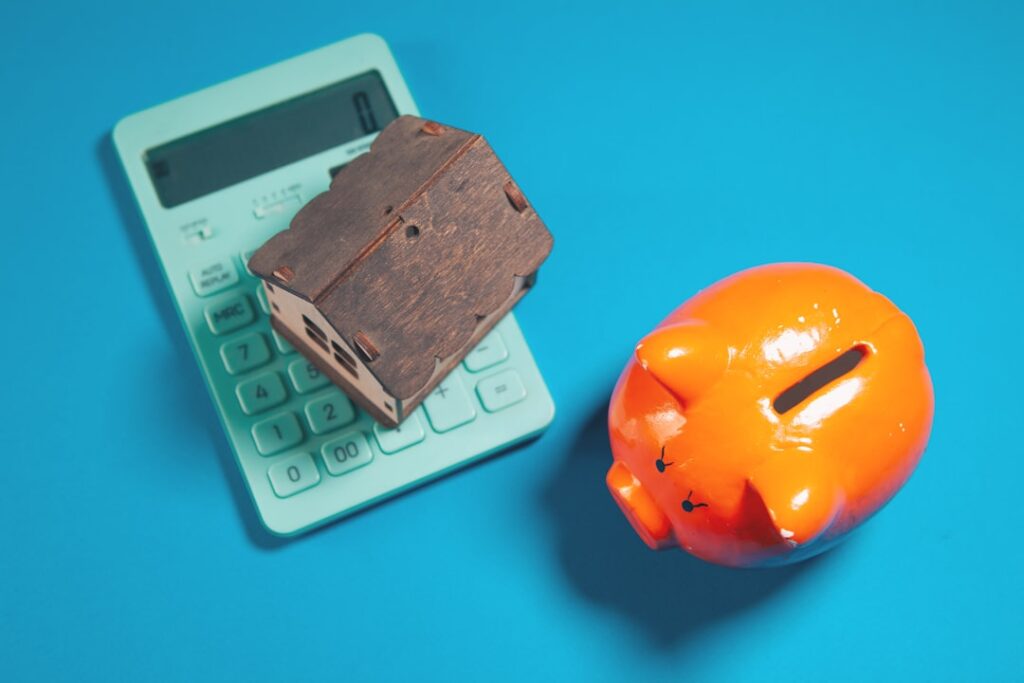 Building Wealth Beyond Paychecks: The Ownership Solution Calculator, piggy bank, and house model on blue background