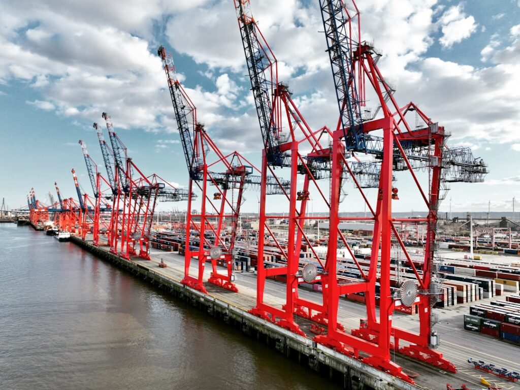 Ningbo's Industrial Evolution: From Manufacturing to Smart Tech Hub Row of red cranes at a busy shipping port.