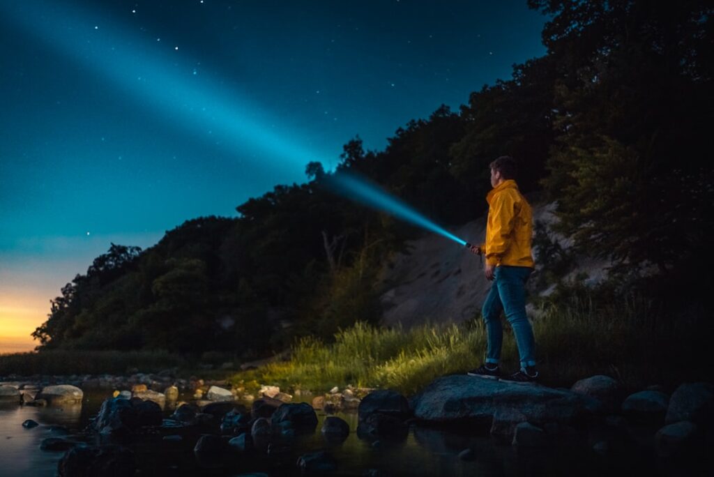 Olight's Earth Month Push: Durable Flashlights Combat Waste man holding flashlight standing on gray stone during nighttime