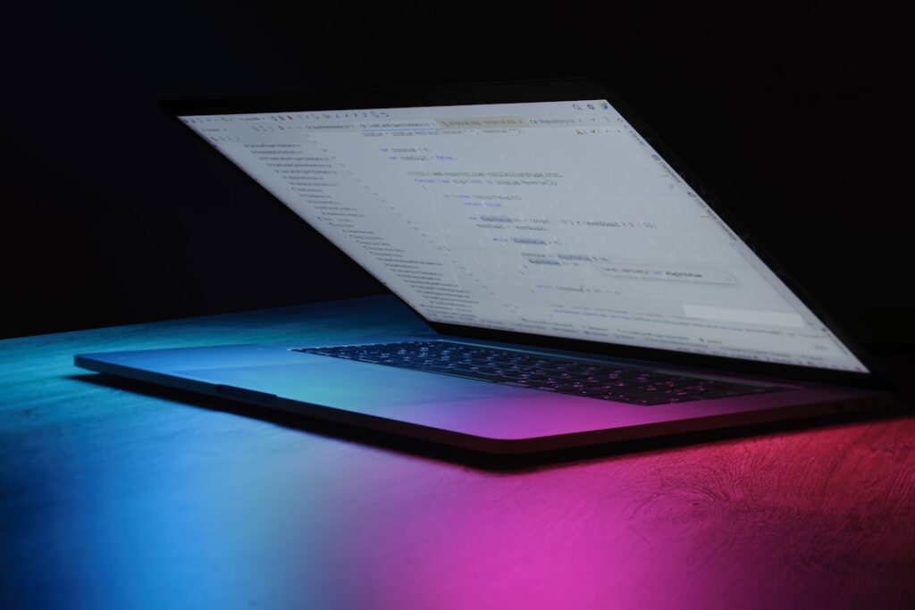 The Hidden Cost of Tokenmaxxing in Software Development Open laptop with code on screen, neon lighting