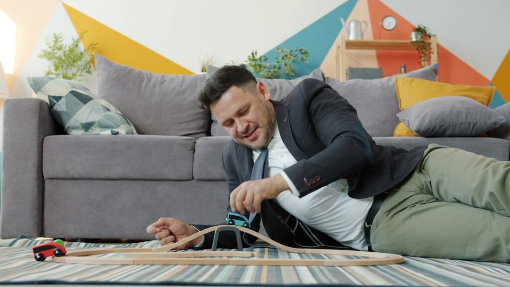 Nissan CEO's Unconventional Stress Management Tactics Revealed Man in suit lying on floor with toy train