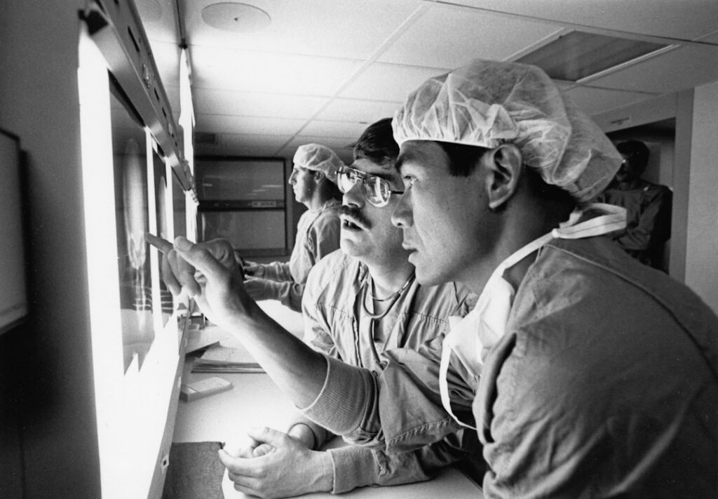 Bracco Imaging Partners with NYU Langone on Medical Imaging Surgeons examining x-rays in a dimly lit room.