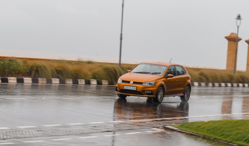 RV Insurance Gaps: What Your Policy Really Covers a small orange car driving down a wet road