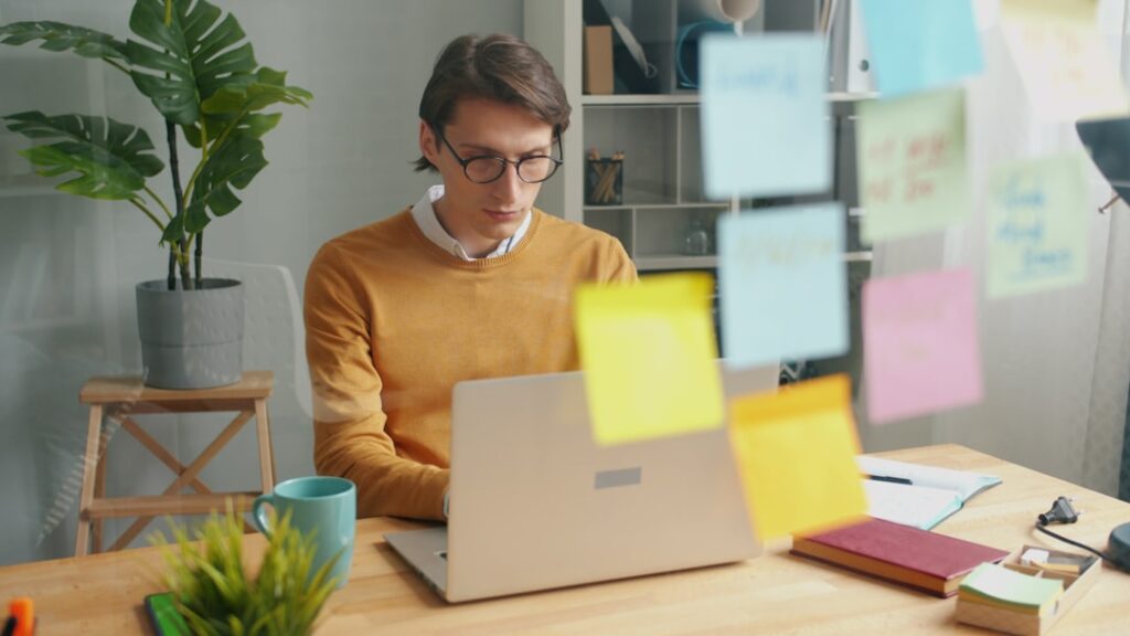 Corporation vs Partnership: Which Structure Fits Your Business? Man working on a laptop with sticky notes