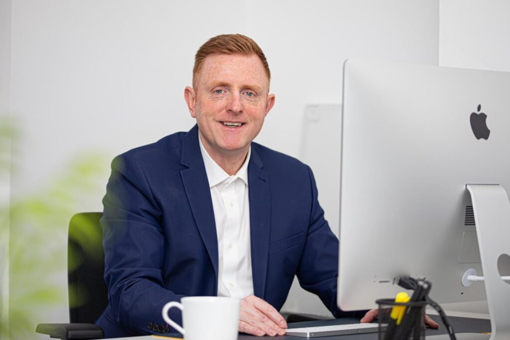 Tim Cook Steps Down as Apple CEO; John Ternus Named Successor man in black suit jacket holding white ceramic mug