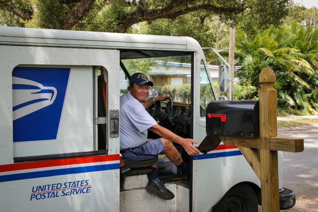 Royal Mail Pressures Part-Time Workers to Boost Letter Delivery man in blue dress shirt sitting on white and blue bus during daytime