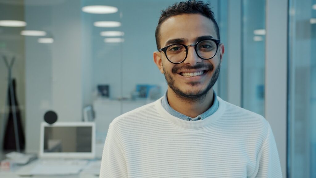 Building Confident Leaders From Your Workforce A smiling man wearing glasses in an office setting.