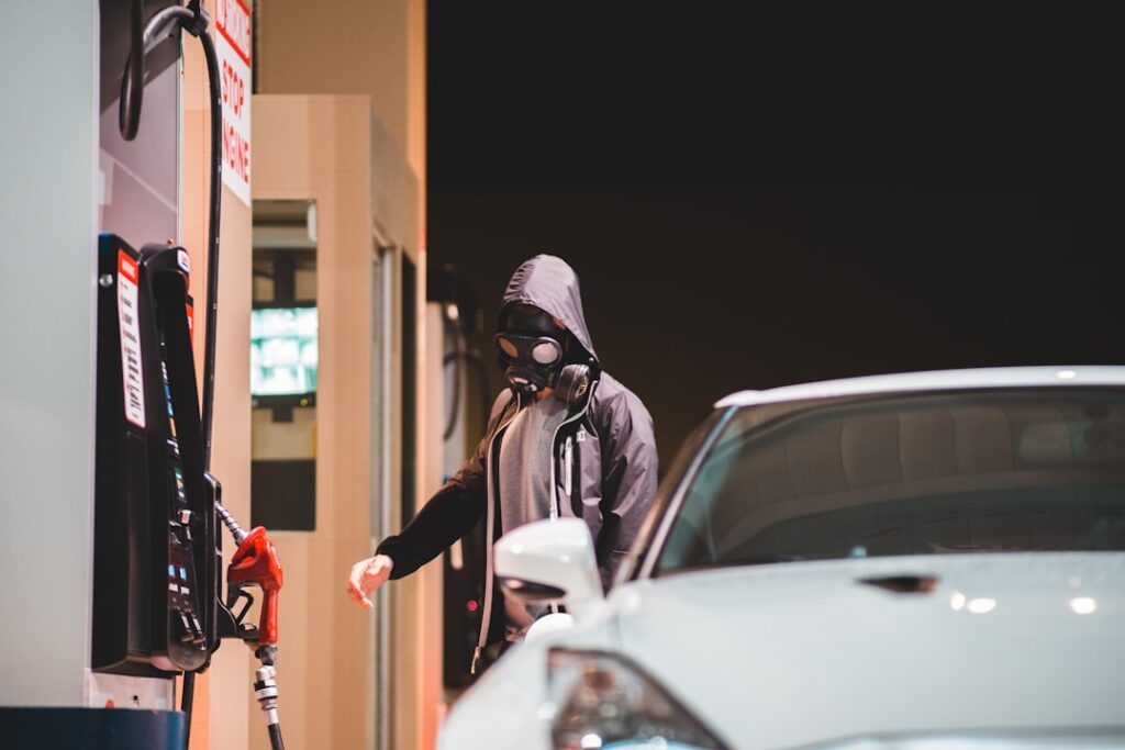 Petrol Theft Surge: Iran Tensions Drive Fuel Crime Up 62% man in black jacket and black knit cap holding red and black umbrella