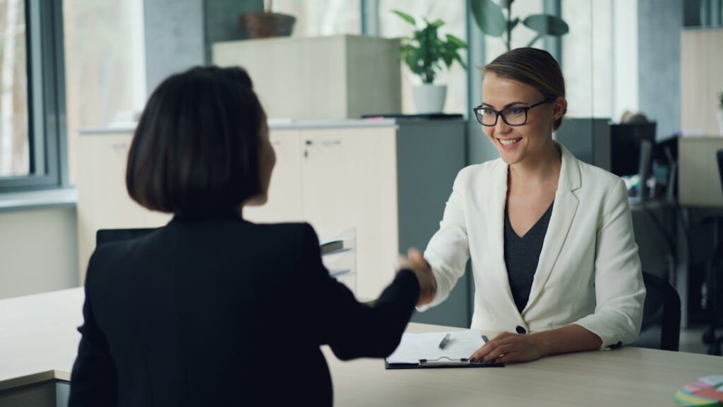 Hiring Right Humans Matters More Than Automation Two women shaking hands across a desk
