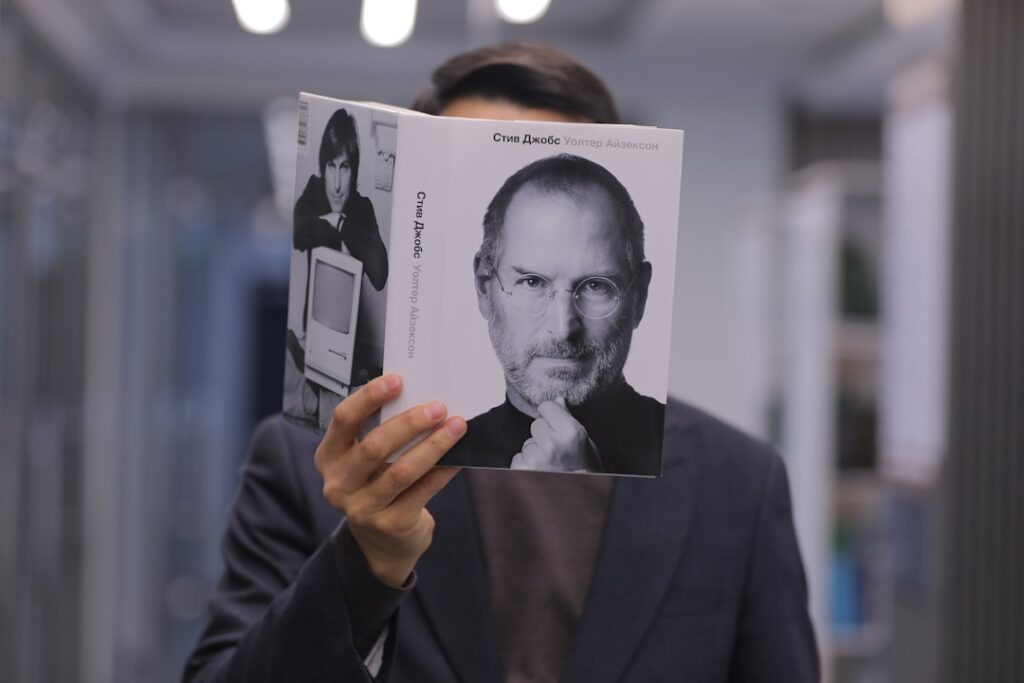 Steve Jobs' Leadership Rule Shapes Apple's Future a man holding up a book with a picture of steve jobs on it