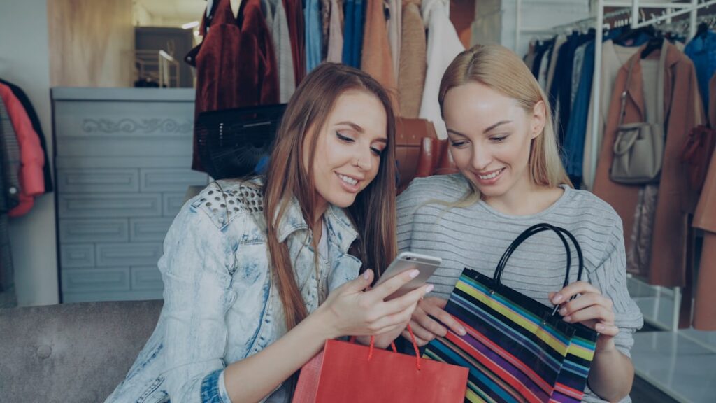 AI Shopping Assistants: The Customer Retention Game Changer Two women shop and look at a phone.