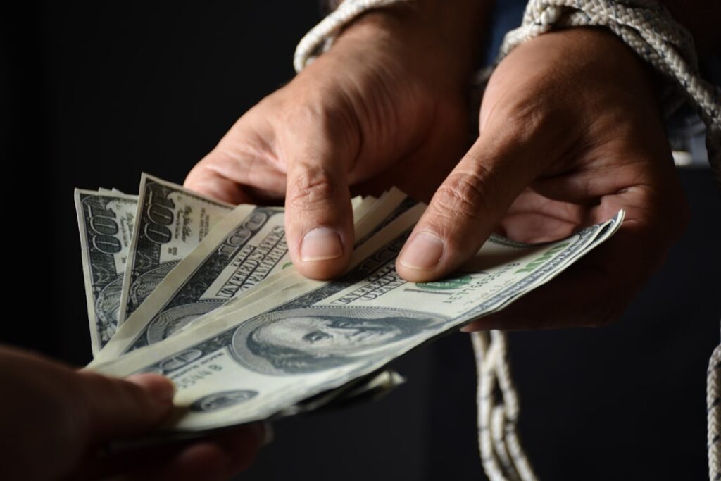 Wage Theft Lawsuit Filed Against Next Level Marking person holding 100 us dollar bill