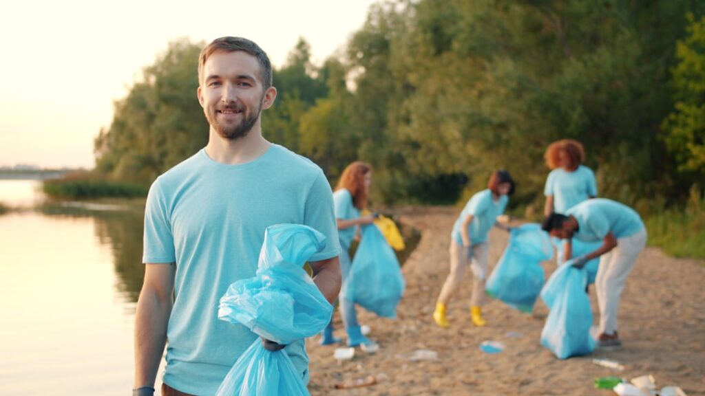 Tru Earth Breaks Guinness Record With 2,082 River Cleanup Volunteers Man holding trash bags with volunteers cleaning beach