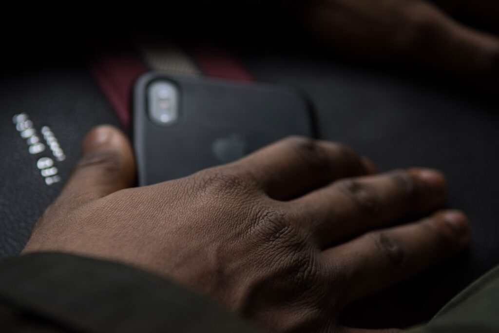 CASEKOO LinKOO Silver Ease: Hands-Free iPhone Innovation person holding black smartphone on black textile