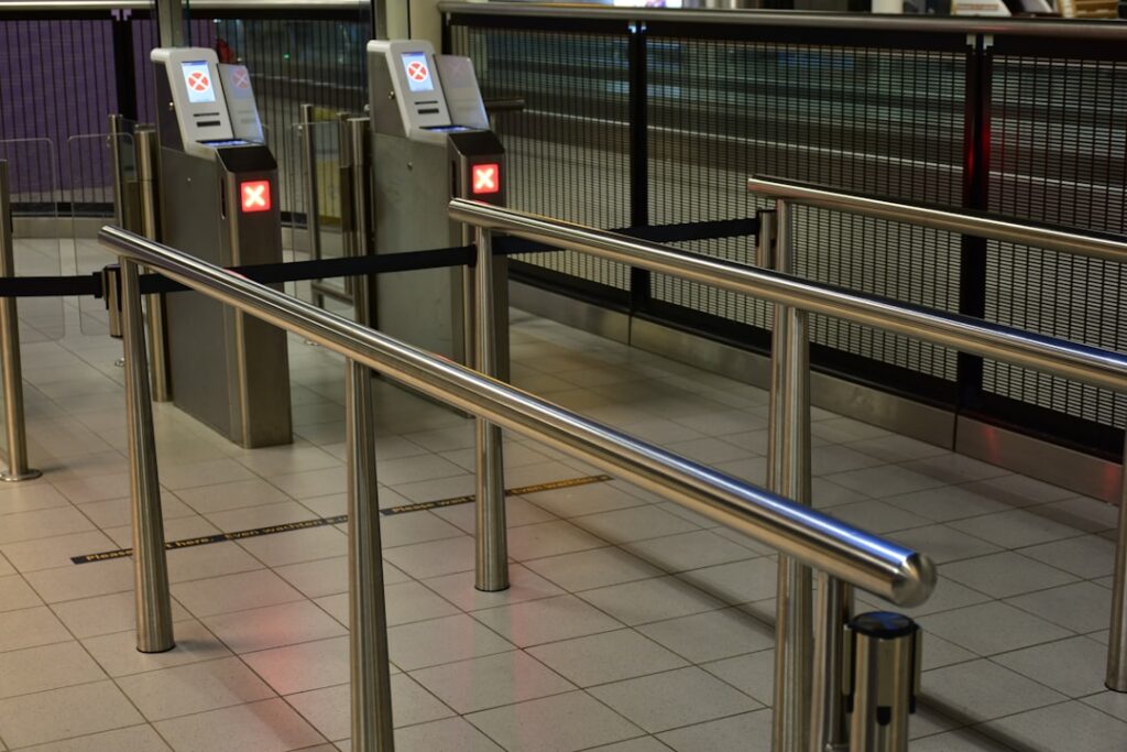 European Border Delays Strand Passengers, Disrupt Flights Metal turnstiles and railings at a transit station.