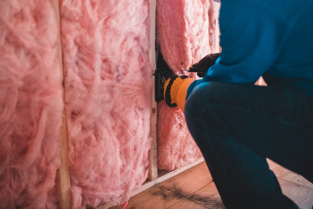 Four Arrested in Home Insulation Fraud Scheme Investigation person in blue pants sitting on brown wooden floor