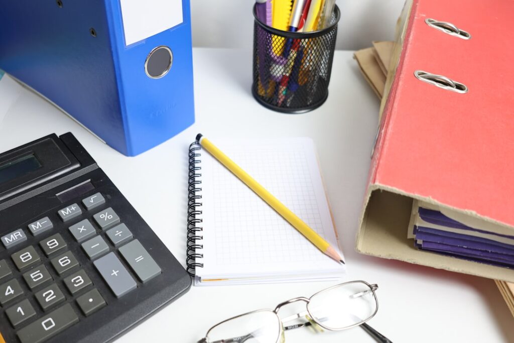 Master Bookkeeping Fundamentals for Business Success Desk with calculator, binders, notebook, and glasses