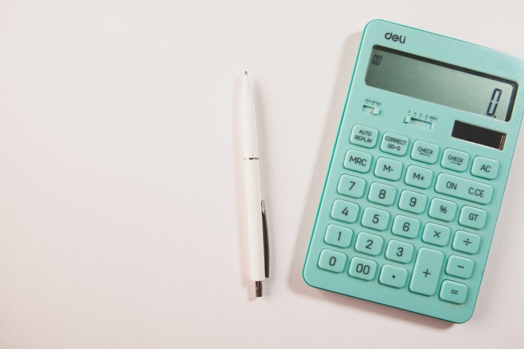 Master Business Finance: Essential Components for Growth A teal calculator and white pen on a white surface.