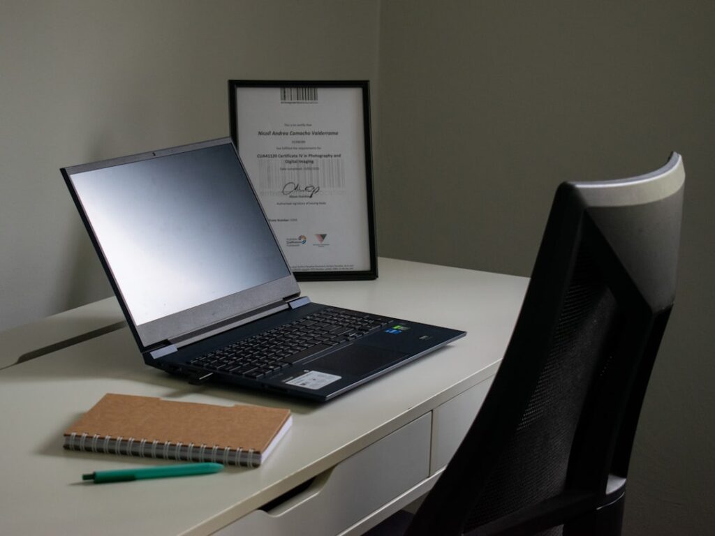 Self-Employment Tax Deductions Guide for 2024 Laptop, notebook, and pen on a desk.