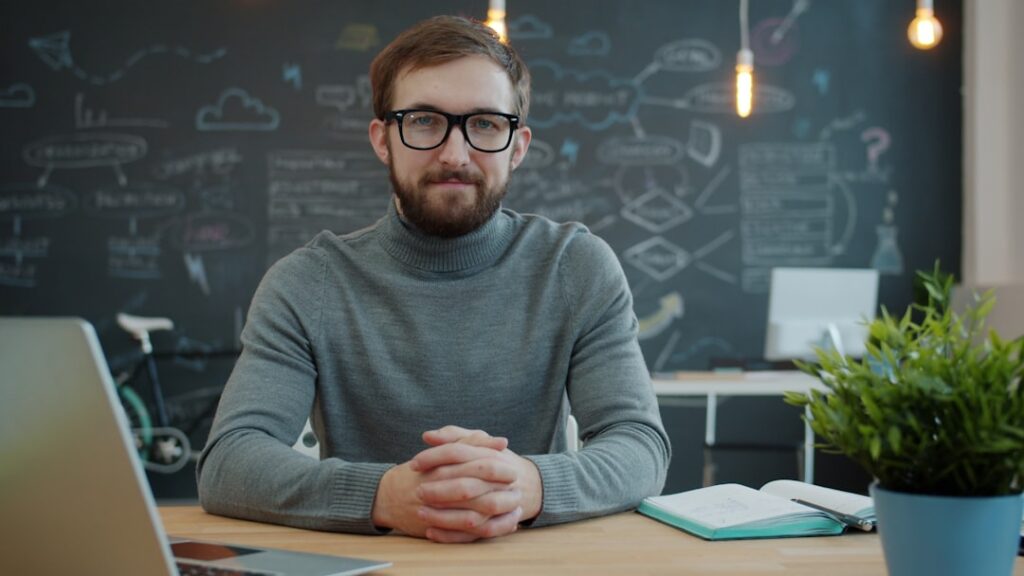 Small Business Agility: The Creative Edge Over Giants Man wearing glasses sits at a desk in office