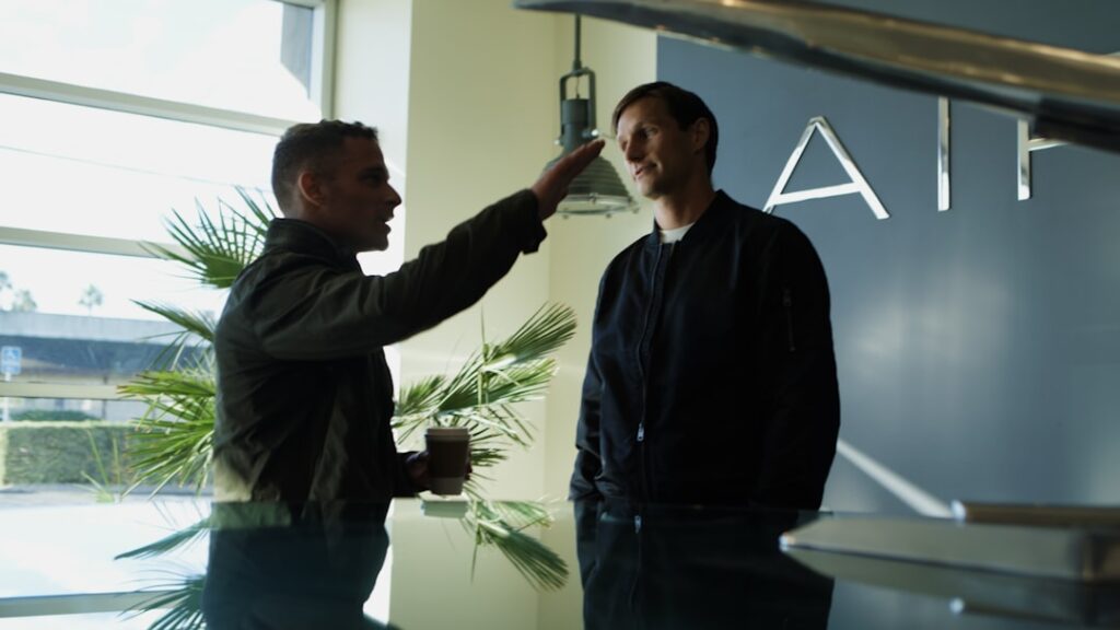 Anthropic's $1.5B Wall Street AI Venture Explained Two men talking near an airplane model.