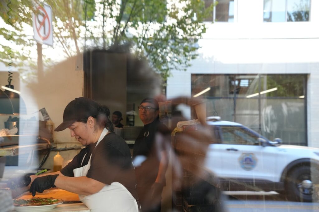 Building Customer Trust Through Operational Excellence Workers prepare food inside a restaurant with police car outside.