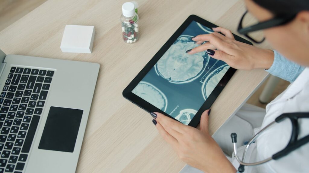 Healthcare Marketplaces Caught Sharing Patient Data With Advertisers Doctor examining brain scan on tablet at desk.