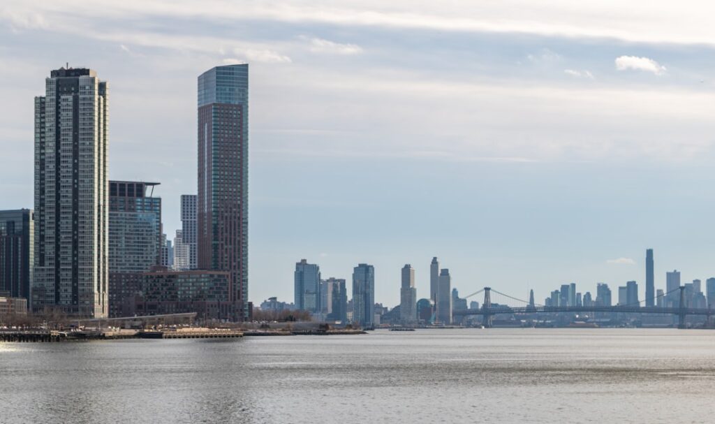 Island Property Prices Drop 5% in Major Market Shift Modern skyscrapers line the waterfront under a cloudy sky.