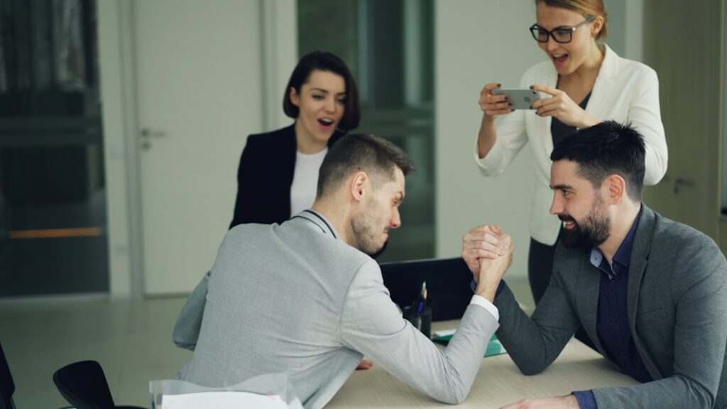 Lovable's Automatic Raises Challenge Corporate Politics Colleagues arm wrestling while others watch and film.
