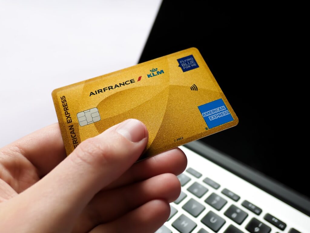 Loyalty Programs: The Complete Business Strategy Guide Hand holding a gold american express card near laptop.