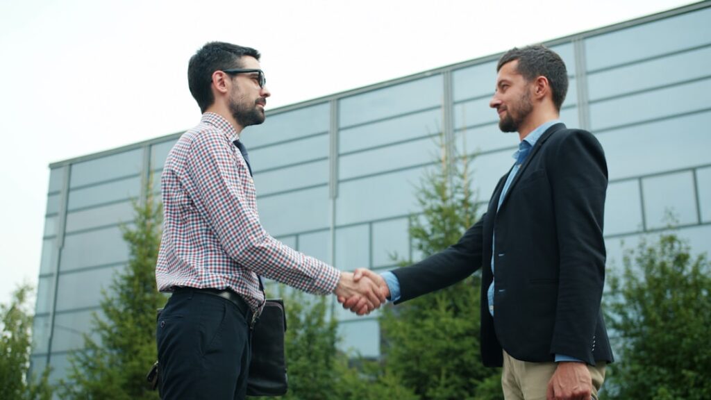 Partnership Red Flags: Protecting Your Business From Value-Draining Partners Two businessmen shaking hands outside modern building