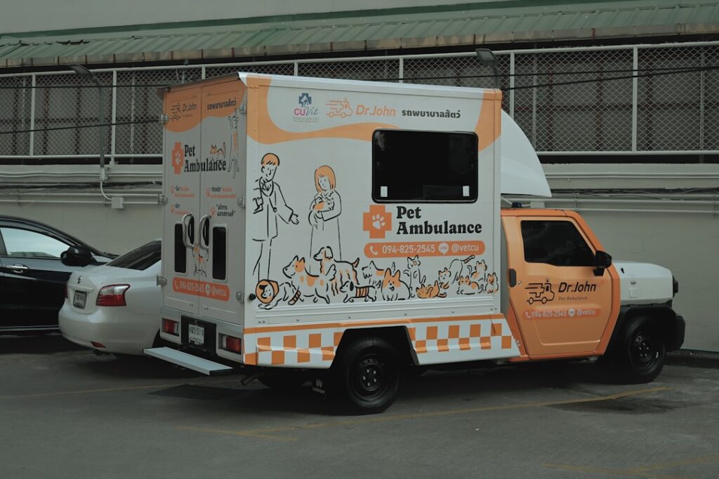 Pet Emergency Bills: Why Insurance Isn't Always Enough A white and orange pet ambulance truck with animal illustrations.