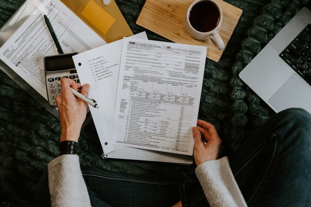 Small Business Financial Reports: Complete Guide Person reviewing documents with calculator and laptop.