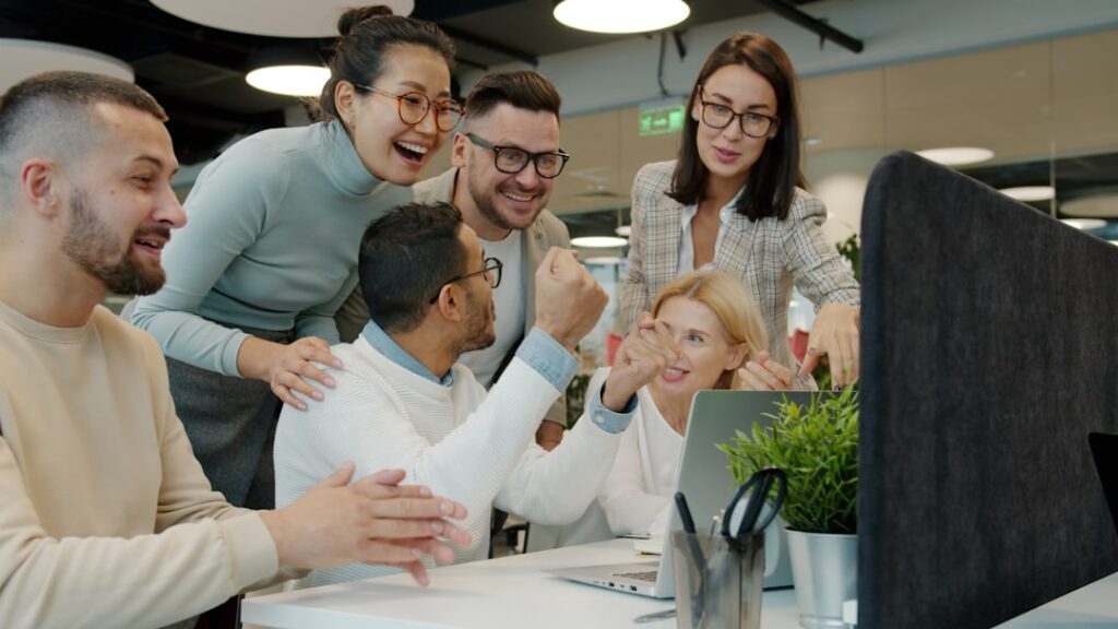 SurveyMonkey's Values Recognition Program Transforms Workplace Culture Diverse team celebrating success at office desk.
