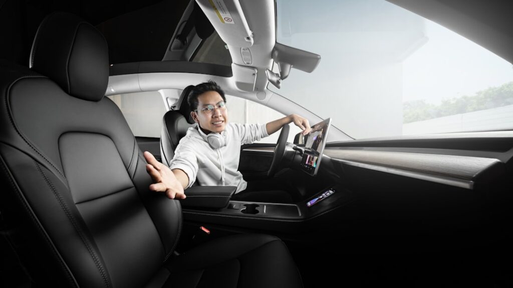 Tesla Model Y First Car to Pass New US Safety Benchmark a man sitting in a car with headphones on