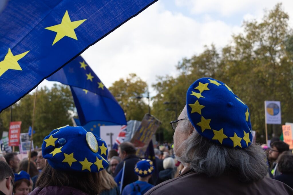 Trump Plans 25% EU Auto Tariff Hike From Current 15% a group of people with blue and yellow hats