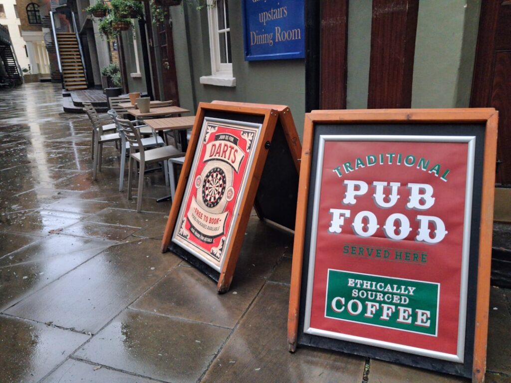 UK Pubs Face Crisis: 161 Closures in First Quarter Two a-frame signs outside a pub on a wet street.